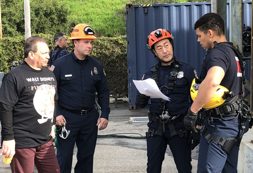 Actors reviewing script lines with firefighters on the set of 9-1-1